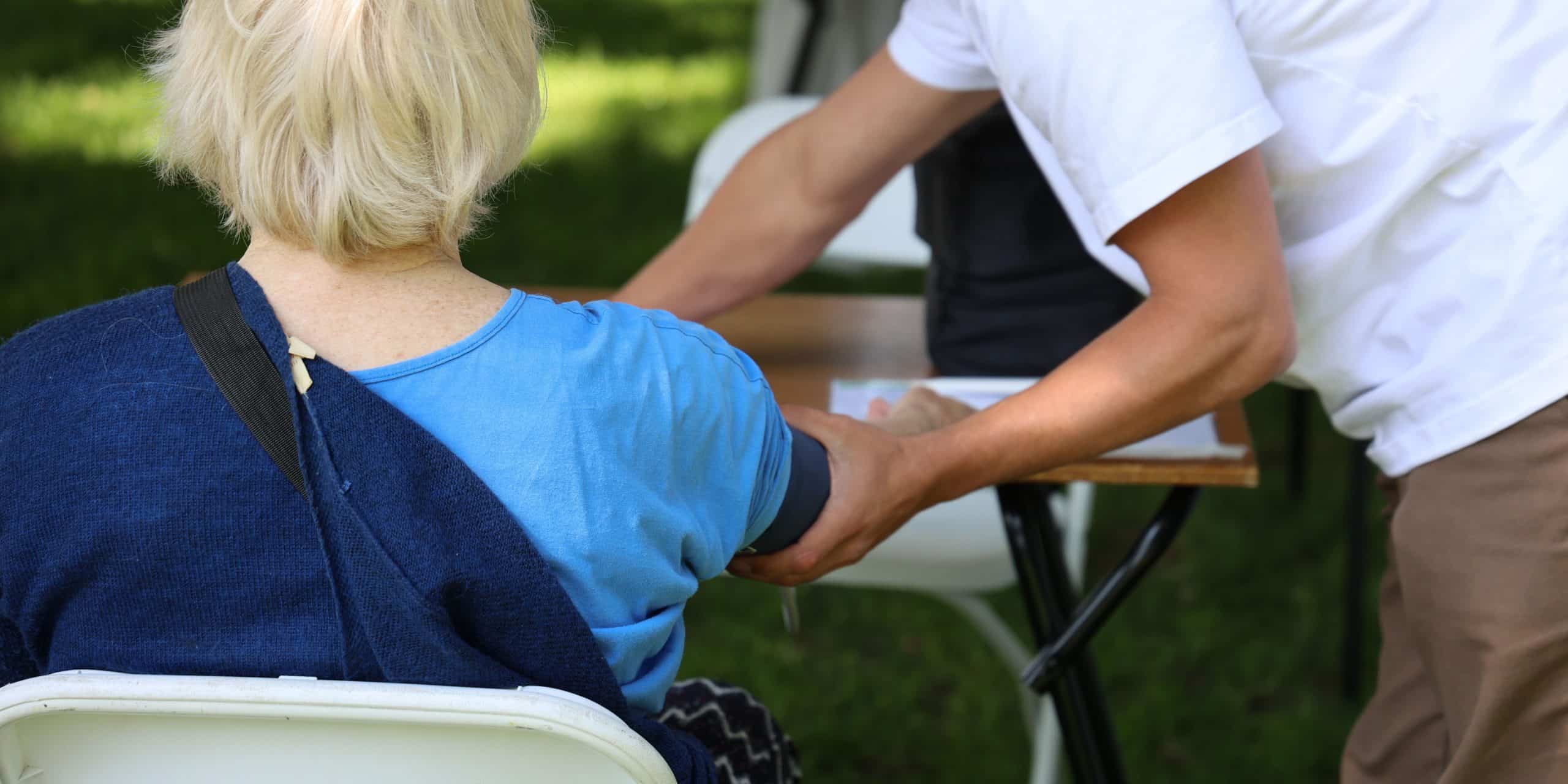 Er wordt een bloeddruk test gedaan door een vrijwilliger bij een oudere dame