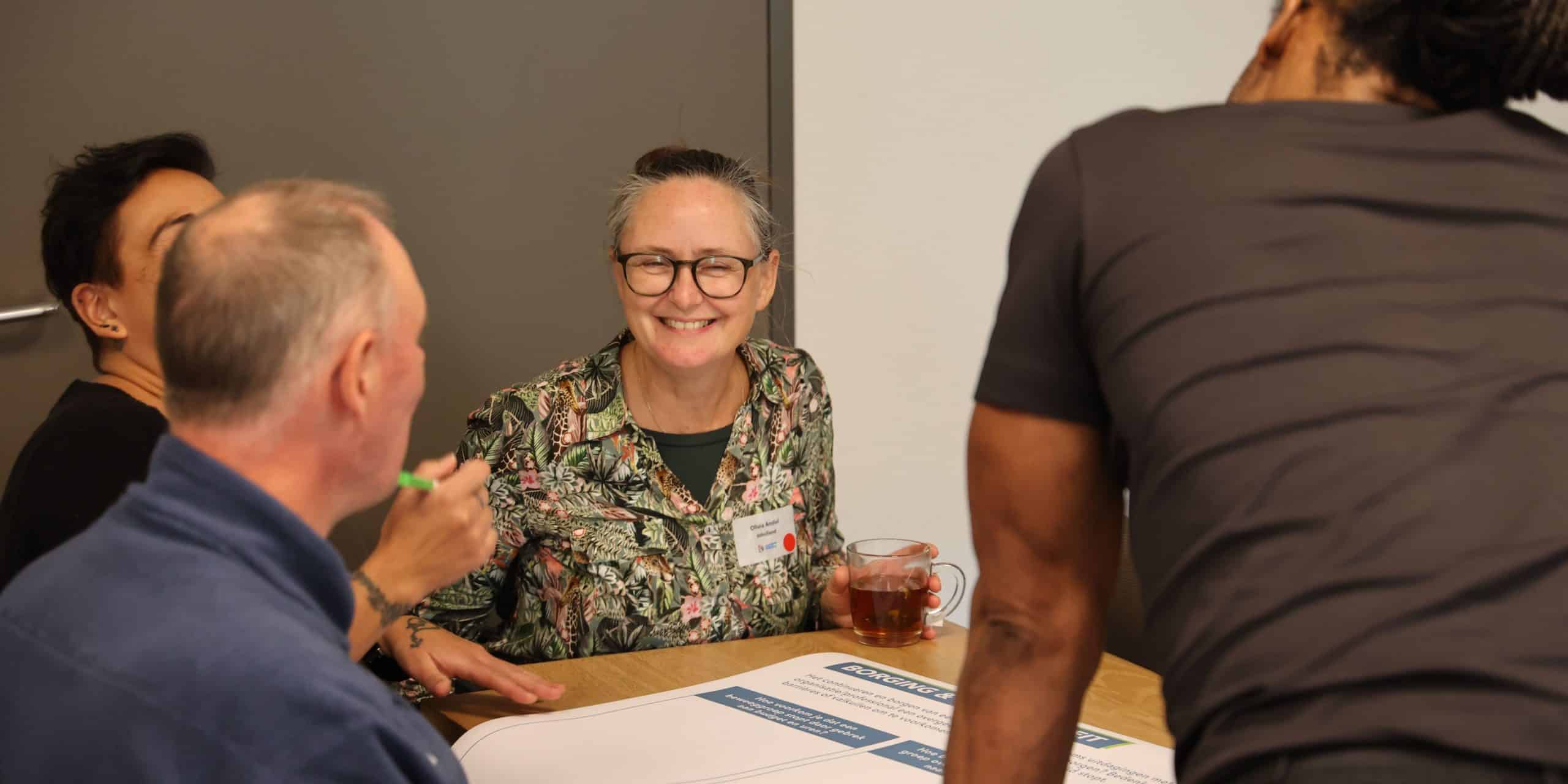 Groepje mensen zit aan een tafel en zijn aan het brainstormen.