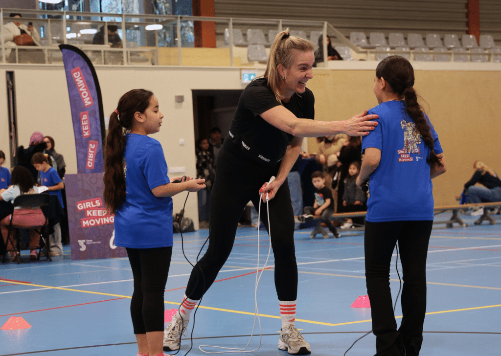 Twee meiden staan bij tonke van tonke springt en tonke geeft een van en lachend een klopje op de schouder